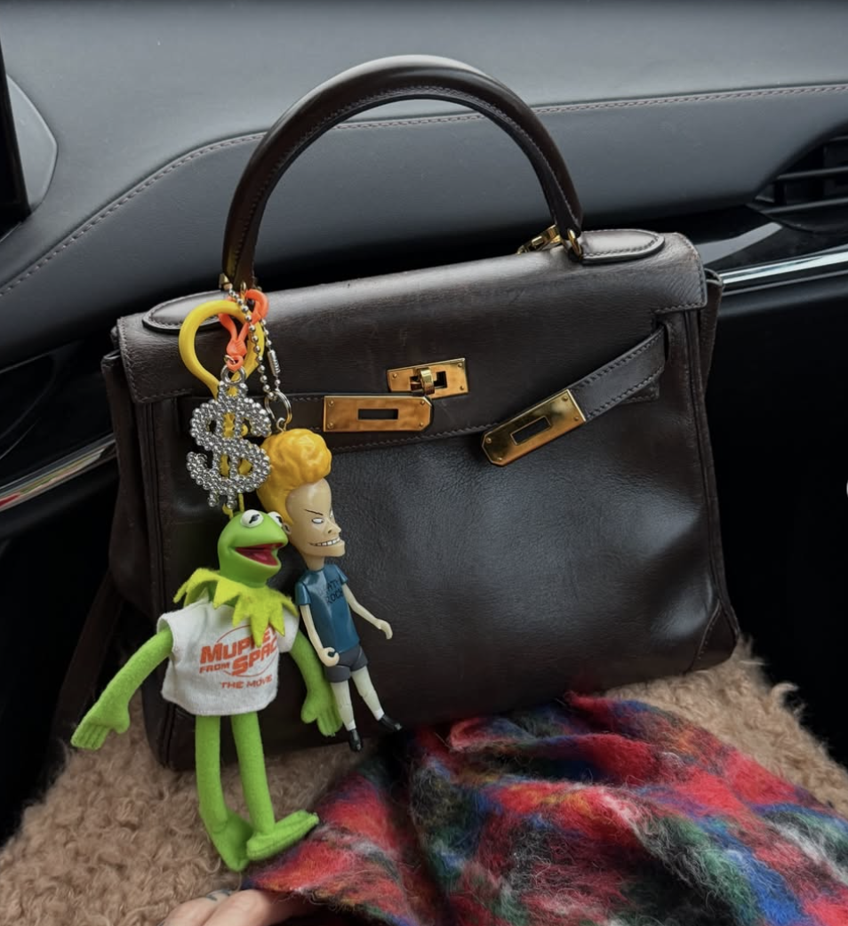 A brown Hermès bag adorned with Kermit the Frog and other vintage character charms.