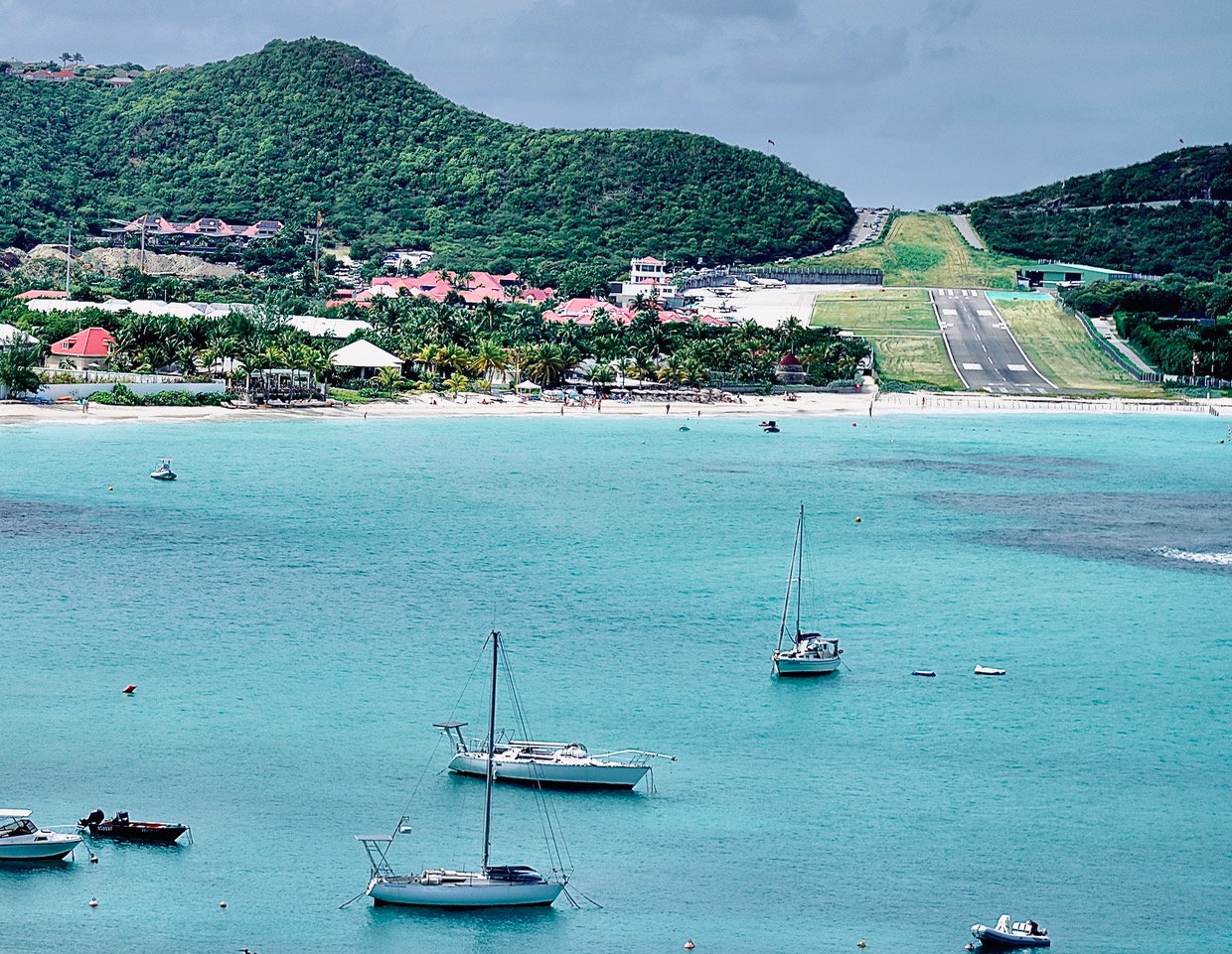 Aerial view of St Barts with its short runway, turquoise water, and sailboats.
