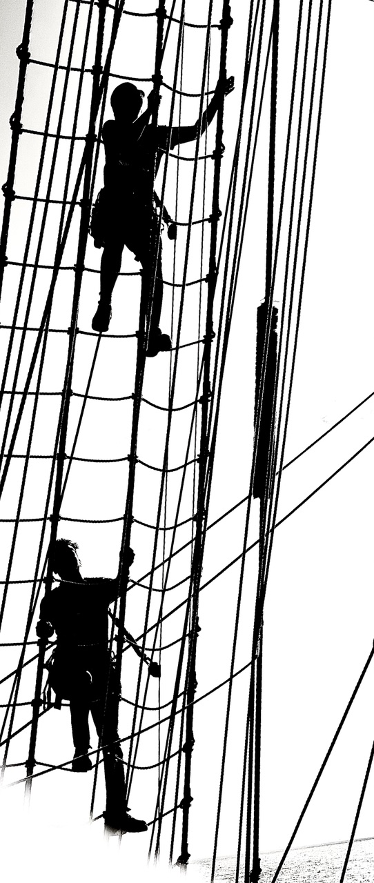 Silhouettes of crew members climbing up the rat lines of the Sea Cloud Spirit.