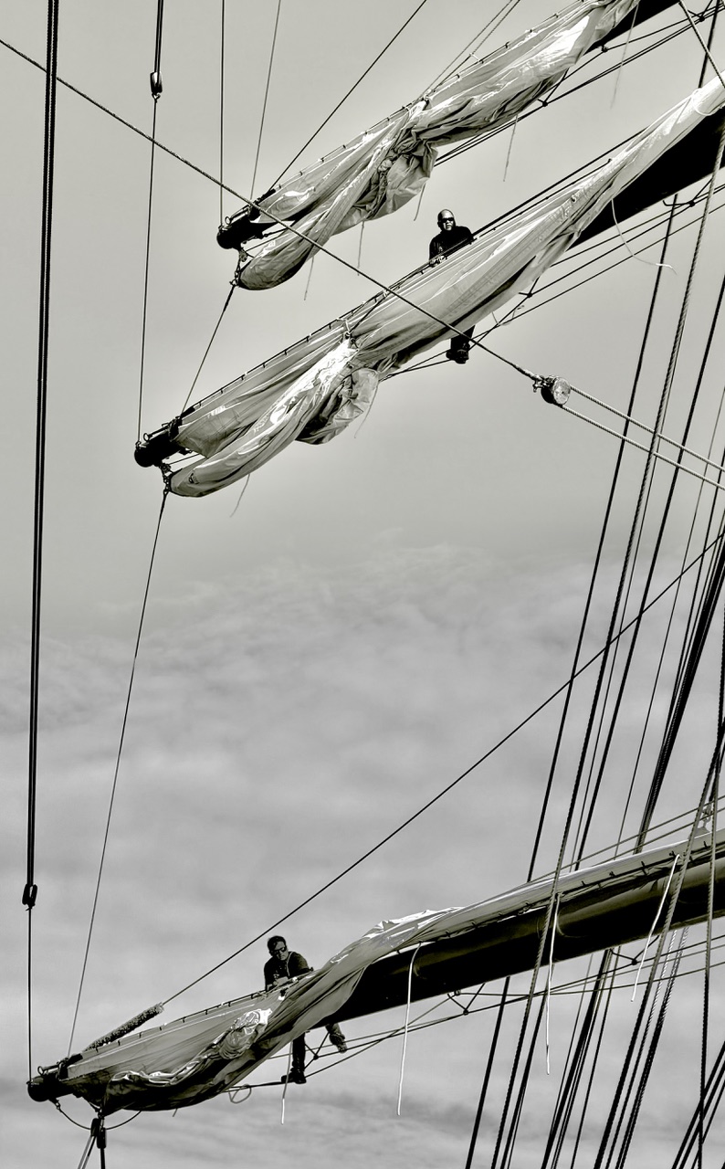 Crew members high on the yards furling the sails of the Sea Cloud Spirit.