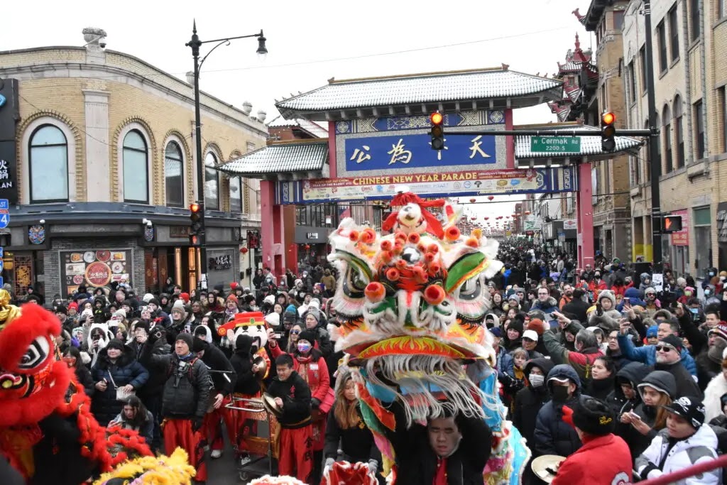 Lion dancers and crowds fill Chinatown's main street beneath the gate arch during the 2026 Lunar New Year Parade