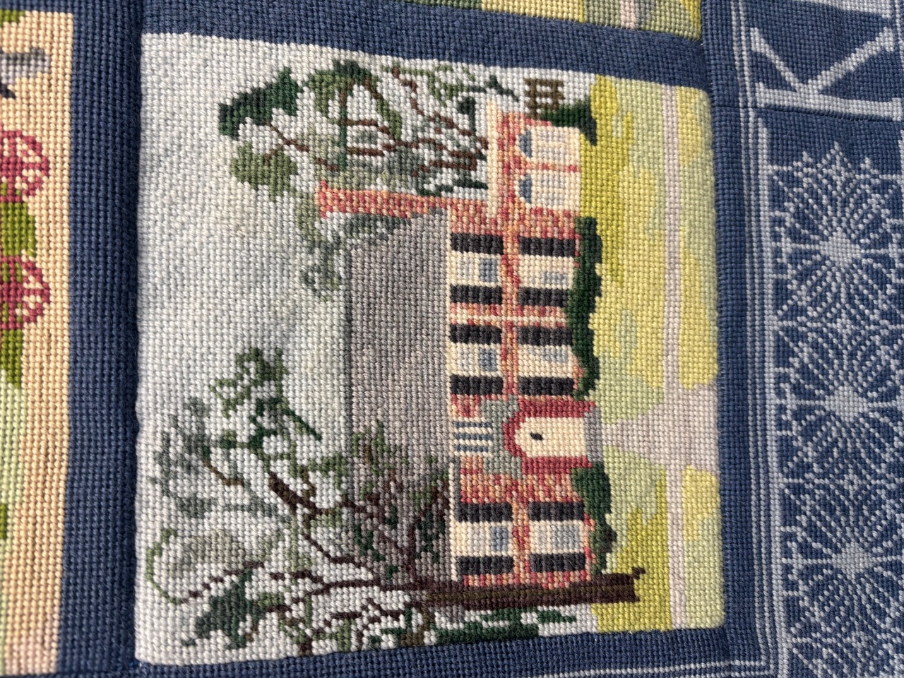 Needlepoint square of a home in town
