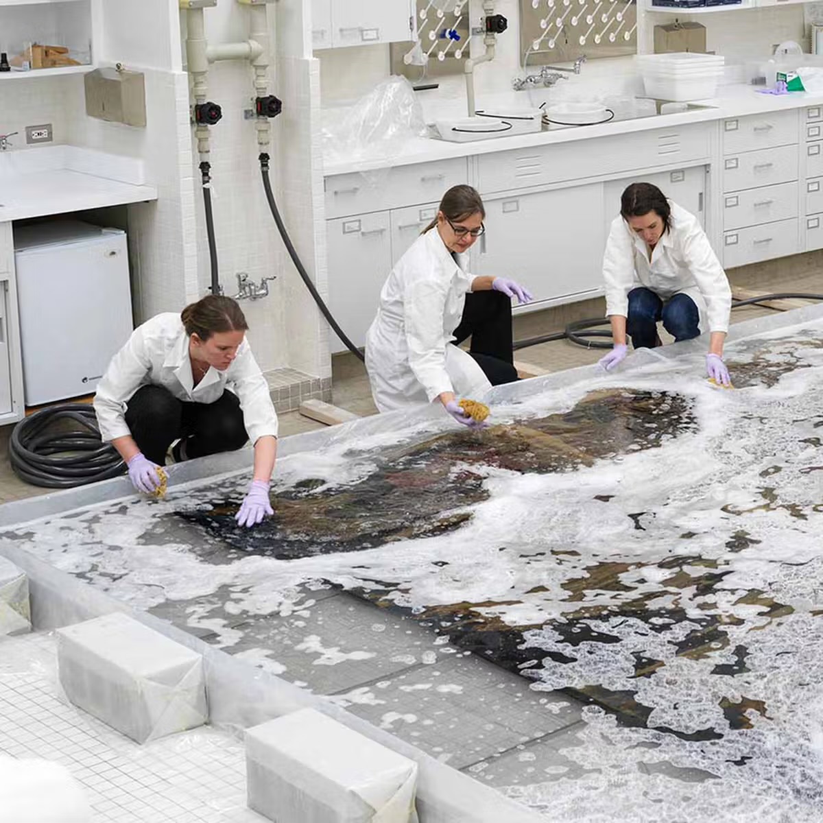 Conservators immersing a tapestry in the wet lab