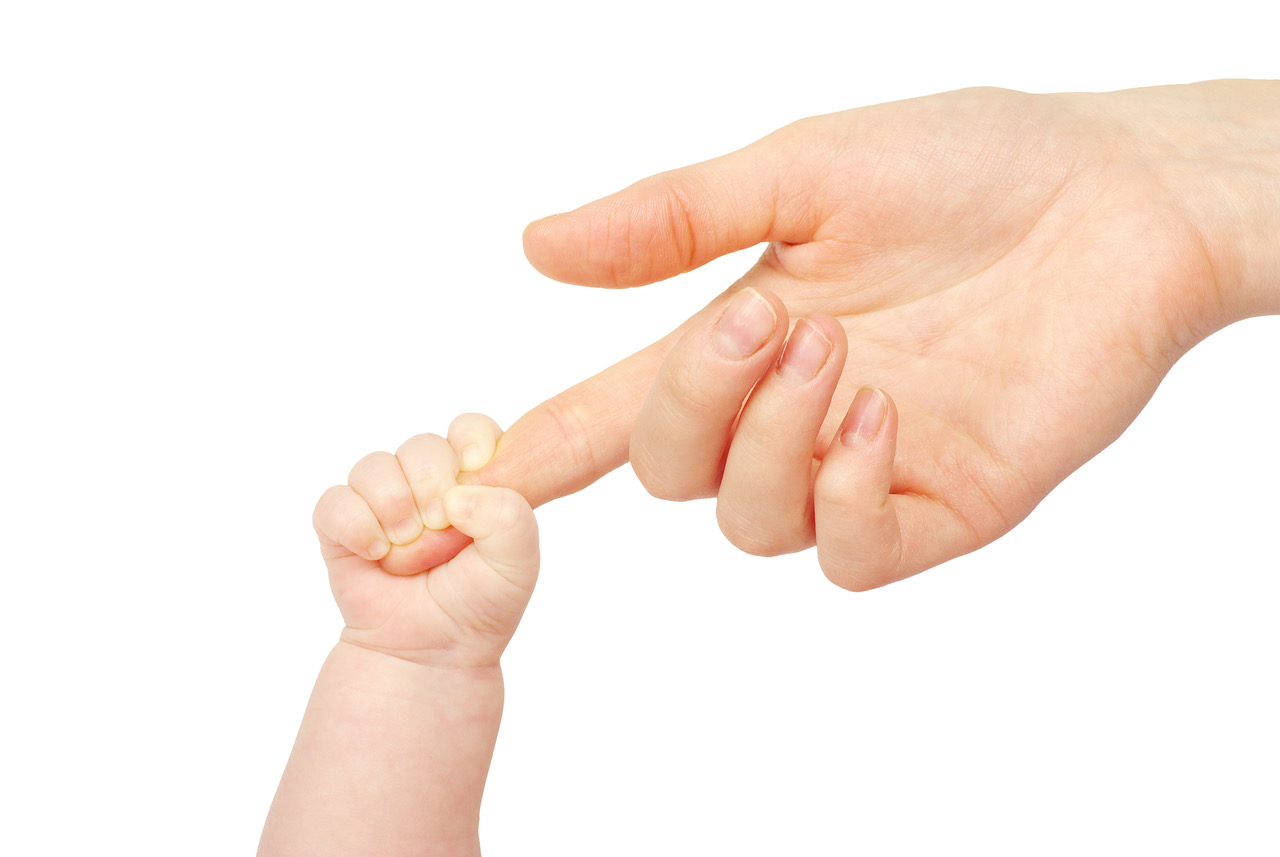 A baby grasping a parent's finger