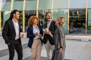 A group of friends laughing together over coffee outside