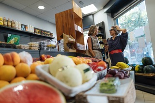 Two women chatting while shopping in a market